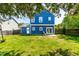 Backyard featuring a blue house, lush green grass, and mature trees at 909 Starkland Way, Holly Springs, NC 27540