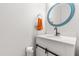 A bathroom featuring a round mirror, white vanity with black hardware, and an orange towel at 909 Starkland Way, Holly Springs, NC 27540