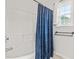 Bright bathroom featuring a white tub with blue curtain, and a window with natural light at 909 Starkland Way, Holly Springs, NC 27540