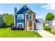 Charming two-story home with blue siding, brick accents, a well-manicured lawn, and a welcoming yellow front door at 909 Starkland Way, Holly Springs, NC 27540