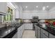A spacious kitchen featuring gray cabinetry, black countertops, stainless steel appliances and tile backsplash at 910 S Third St, Mebane, NC 27302