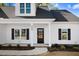 Inviting front entrance with black door, trimmed windows, and manicured landscaping at 9200 Otter Ct, Middlesex, NC 27557