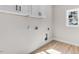 This laundry room features a window, white shaker cabinets and vinyl wood flooring at 9200 Otter Ct, Middlesex, NC 27557