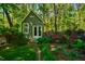 Quaint green outbuilding surrounded by lush landscaping and a charming garden at 102 Antler Point Rd, Chapel Hill, NC 27516