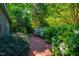 Brick path with lush plantings and flower beds in the peaceful backyard at 102 Antler Point Rd, Chapel Hill, NC 27516
