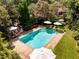 Backyard pool with brick border, lounge chairs, and umbrellas surrounded by mature trees at 102 Antler Point Rd, Chapel Hill, NC 27516