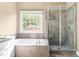 Elegant bathroom showcasing a window-side soaking tub and glass shower at 102 Traviliah Oaks Ln, Cary, NC 27518