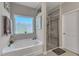 Bright bathroom featuring soaking tub, glass door shower, and a large window at 106 Neuse Bluff Cir, Clayton, NC 27527