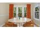 Cozy dining room with oval table, wood chairs, and large windows with vibrant orange curtains at 110 Chapelwood Way, Cary, NC 27518