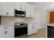 Modern kitchen showcasing stainless steel appliances, quartz countertops, white cabinets and herringbone backsplash at 110 Chapelwood Way, Cary, NC 27518