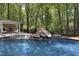 Backyard pool features a slide, rock waterfall, lounge area with fireplace, and mature trees at 110 Chapelwood Way, Cary, NC 27518