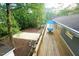 Elevated view of the wooden deck, outdoor table, and patio space, surrounded by lush greenery and tall trees at 1124 Hardimont Rd, Raleigh, NC 27609