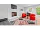 Bright living room featuring a fireplace, gray sofa, and unique mid-century modern red chairs at 1124 Hardimont Rd, Raleigh, NC 27609