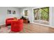 Bright living room with a walk-out, featuring hardwood floors, and mid-century modern red chairs at 1124 Hardimont Rd, Raleigh, NC 27609