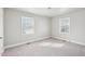 Sunlit bedroom featuring neutral carpet, two windows, and painted walls at 115 Higbee St, Durham, NC 27704