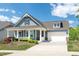 Charming blue home featuring a welcoming front porch, two-car garage, and beautifully landscaped yard at 1208 Steinbeck Dr, Durham, NC 27703