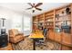 Well-lit home office featuring custom built-in bookshelves, a ceiling fan, and a comfortable workspace at 1208 Steinbeck Dr, Durham, NC 27703