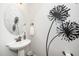 Elegant powder room features a pedestal sink, floral artwork, and modern fixtures at 1208 Steinbeck Dr, Durham, NC 27703