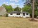 Well-maintained white brick home with a spacious lawn and mature trees, perfect for outdoor enjoyment at 1310 Mayfair Rd, Raleigh, NC 27608