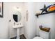 Cozy half-bathroom with pedestal sink, decorative accents, and stylish wooden shelf at 1403 Chipping Dr, Apex, NC 27502