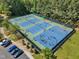 Aerial view showcasing tennis and basketball courts, surrounded by lush trees and greenery at 1420 Willowleaf Way, Apex, NC 27502