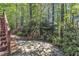 View of a backyard with a stone patio, lush greenery, and flowering bushes, creating a tranquil outdoor space at 1420 Willowleaf Way, Apex, NC 27502