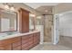 Spacious bathroom featuring dual sinks with dark wood cabinets, and tiled shower with glass door at 1420 Willowleaf Way, Apex, NC 27502