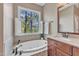 Relaxing bathroom showcasing a soaking tub next to a window with nature view and sink vanity at 1420 Willowleaf Way, Apex, NC 27502