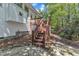 Back exterior view of the home showing stairs leading to a stone patio, surrounded by landscaping and lush greenery at 1420 Willowleaf Way, Apex, NC 27502
