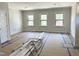 Bright living room featuring three windows offering ample natural light and unfinished wood floors at 1448A Maplewood Dr, Durham, NC 27704
