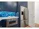 Modern kitchen with stainless steel refrigerator, built-in oven, blue cabinets, and quartz countertop at 1616 Hunting Ridge Rd, Raleigh, NC 27615