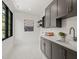 Laundry room with gray cabinets, stainless steel sink, white tile floors and black window at 1616 Hunting Ridge Rd, Raleigh, NC 27615