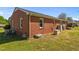 Backyard view of the brick home featuring a covered basement exit and green lawn at 1802 Prince Edward Dr, Elon, NC 27244