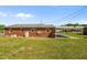 Backyard view of the exterior of the brick home featuring a covered parking area and lawn at 1802 Prince Edward Dr, Elon, NC 27244