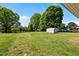A spacious backyard featuring mature trees, a storage shed, and an expansive lawn area at 1802 Prince Edward Dr, Elon, NC 27244