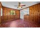 Living room with knotty pine walls, vintage ceiling fan, and view into the kitchen at 1802 Prince Edward Dr, Elon, NC 27244