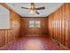 Living area with knotty pine walls, vintage ceiling fan, and a window at 1802 Prince Edward Dr, Elon, NC 27244