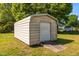 View of the exterior of a gray storage shed with a roll-up door and an ample backyard at 1802 Prince Edward Dr, Elon, NC 27244