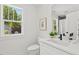 A bathroom with white cabinets, a framed print, and a bright window overlooking a yard at 2019 James St, Durham, NC 27707