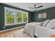 Well-lit bedroom with three large windows, a ceiling fan, hardwood floors and tasteful decor at 2019 James St, Durham, NC 27707