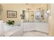 Elegant bathroom with dual sinks, white cabinets, marble countertops, and a large soaking tub at 205 Lippershey Ct, Cary, NC 27513