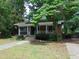 Cozy brick home featuring a screened porch, inviting entrance, and mature trees at 223 S Main St, Wendell, NC 27591