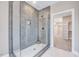 Modern shower with glass door, grey tiled walls, and white tile flooring, leading to a closet at 2437 Terri Creek Dr, Fuquay Varina, NC 27526