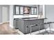 Stylish home bar with modern gray cabinetry, glass shelving, and sleek black countertop seating four at 25303 Ludwell, Chapel Hill, NC 27517