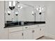 Bathroom vanity featuring black countertop, white cabinets, and a large mirror with unique light fixtures at 25303 Ludwell, Chapel Hill, NC 27517