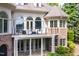 Rear exterior view of home showcasing deck with black metal railing and lower level patio at 25303 Ludwell, Chapel Hill, NC 27517