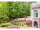 Home exterior featuring a stone retaining wall, lush trees, and an outdoor dining area at 25303 Ludwell, Chapel Hill, NC 27517