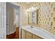 Well-maintained bathroom with a white vanity, mirror, and decorative wallpaper at 3100 Coachmans Way, Durham, NC 27705