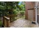View of the wooden deck and wooded scenery from the side of a red brick home at 3100 Coachmans Way, Durham, NC 27705