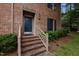 Close-up of the home's front entrance featuring a blue door, brick steps, and manicured landscaping at 3100 Coachmans Way, Durham, NC 27705